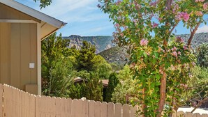 A wooden fence, a tree with pink flowers, and a mountainous landscape in the background. - Modern Zen Luxury · With Views · Centrally Located (Sedona)