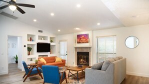 A modern living room with a fireplace, a flat-screen TV, and a ceiling fan. - Modern Zen Luxury · With Views · Centrally Located (Sedona)