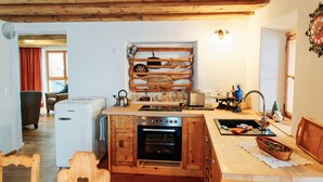 A compact kitchen with wooden cabinetry, a built-in oven, and a small island with a sink. - Vacation home Fichte (4822 Bad Goisern am Hallstättersee)