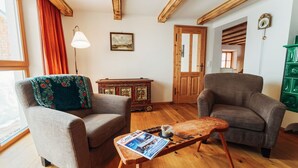 A living room with two armchairs, a wooden coffee table with magazines, a floor lamp, a painting, and a green cabinet. - Vacation home Fichte (4822 Bad Goisern am Hallstättersee)