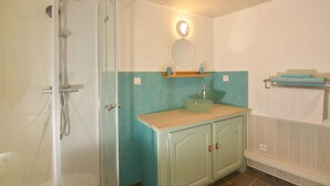A bathroom with a shower, a sink with a mirror above it, and a towel rack.