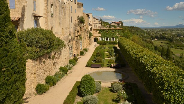 A historic stone building with a garden pathway leading to a pond.