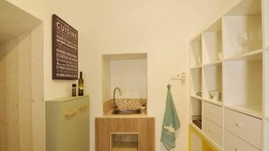 A compact kitchen with a sink, a small cabinet, and a wine bottle on the counter.