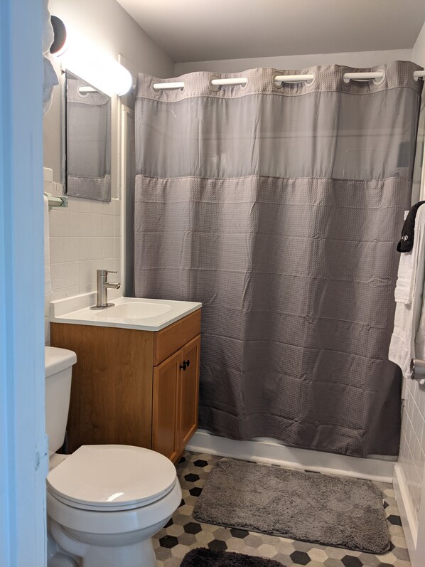 Ein Badezimmer mit Toilette, Waschbecken, Waschtisch, Duschvorhang und Teppich.