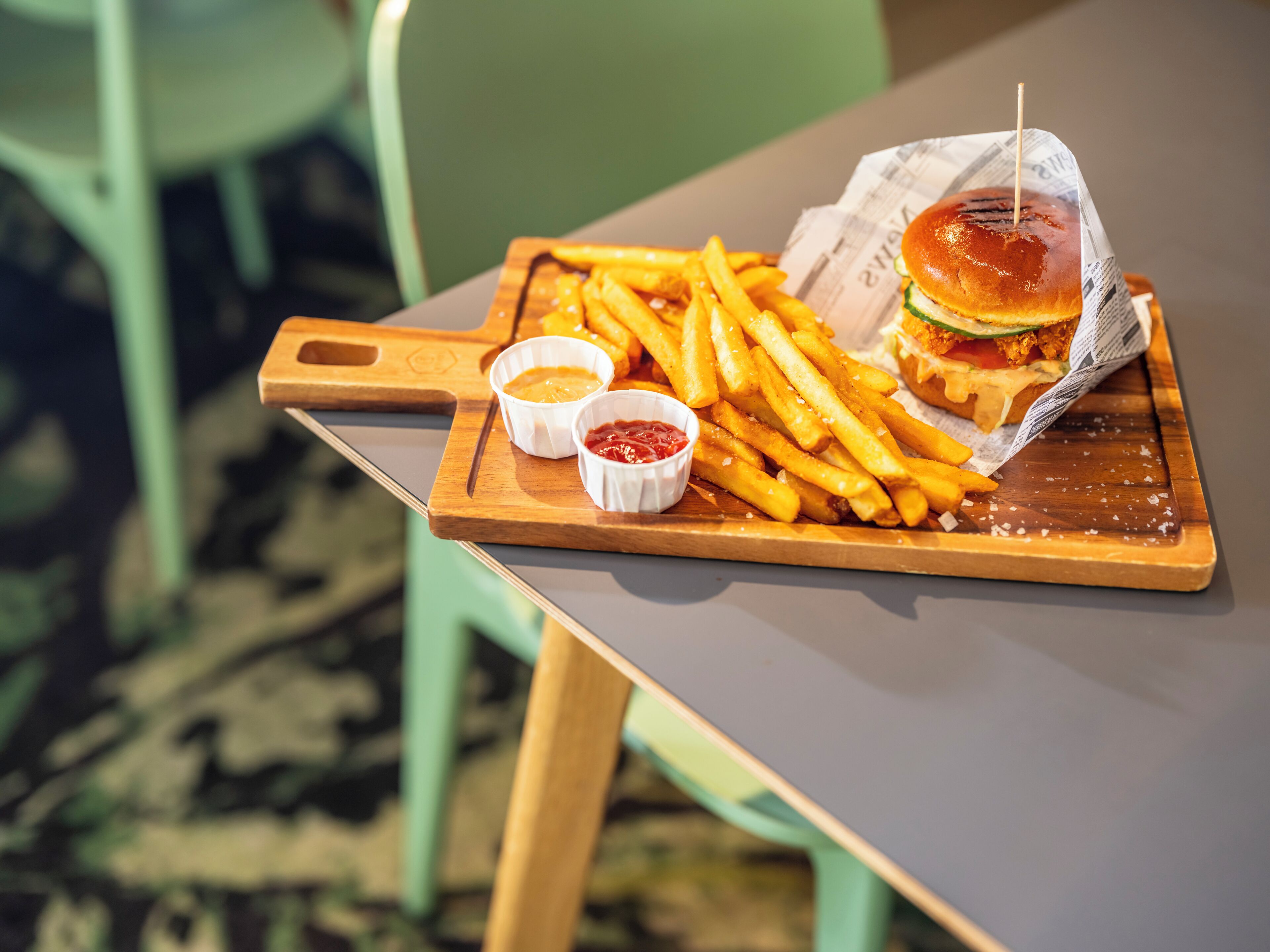 En træbakke med en burger og pommes frites på et bord.