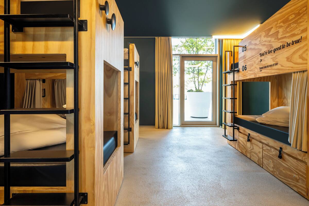 Une chambre moderne et compacte, dotée de lits superposés, d’un petit placard et offrant une vue sur l’extérieur grâce à une grande fenêtre.