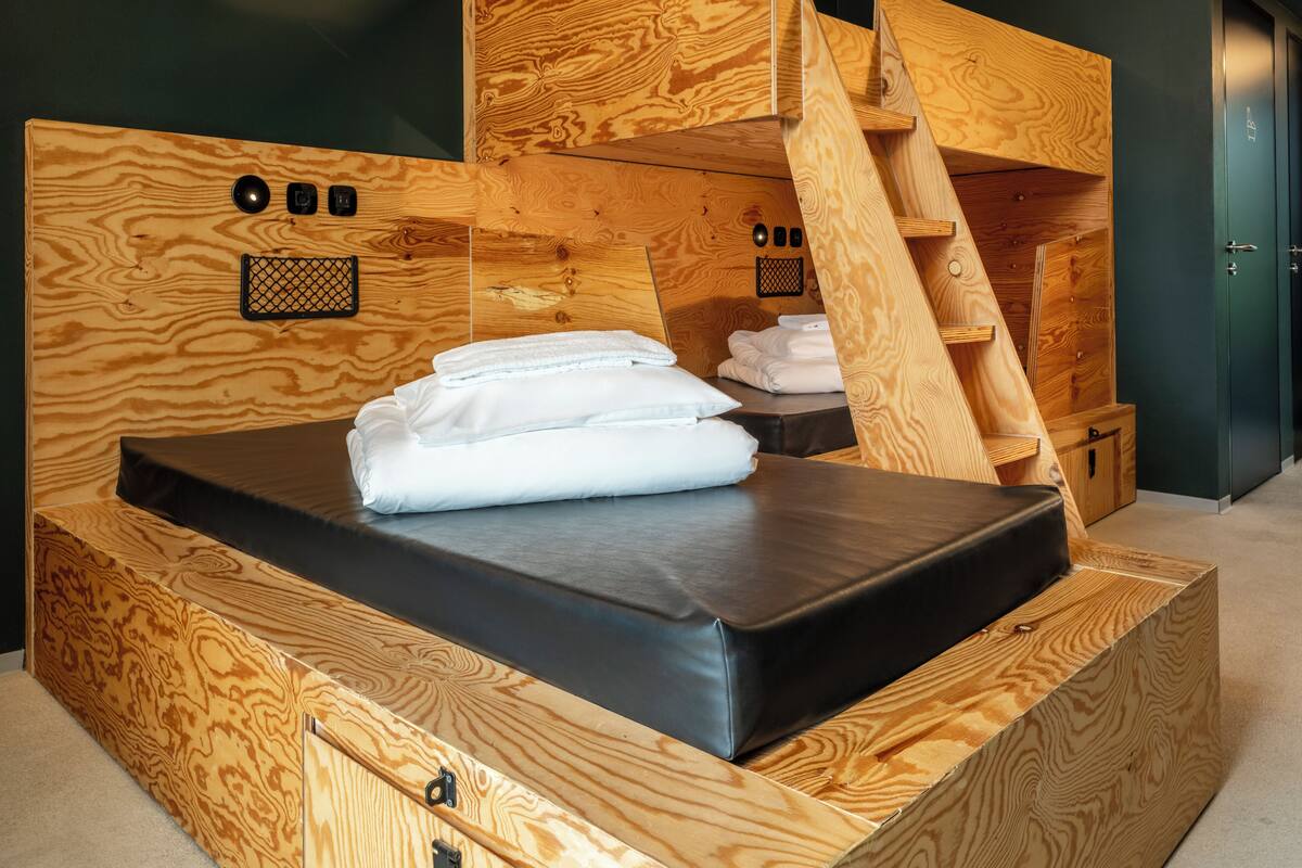 Une pièce en bois contenant un lit, une commode en bois et un petit meuble en bois.