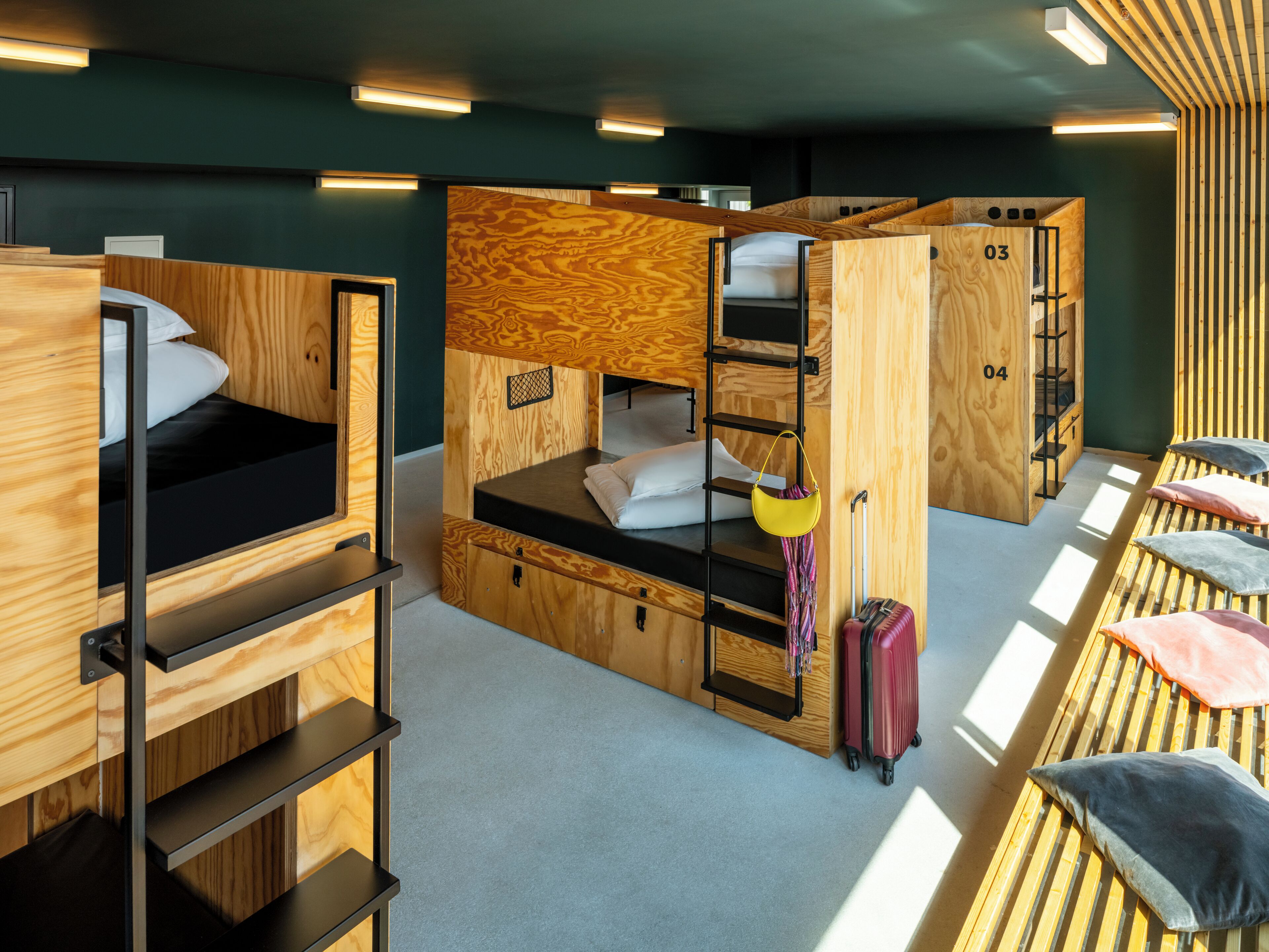 Una habitación compacta y moderna con literas, paredes de madera y una pequeña zona de escritorio.