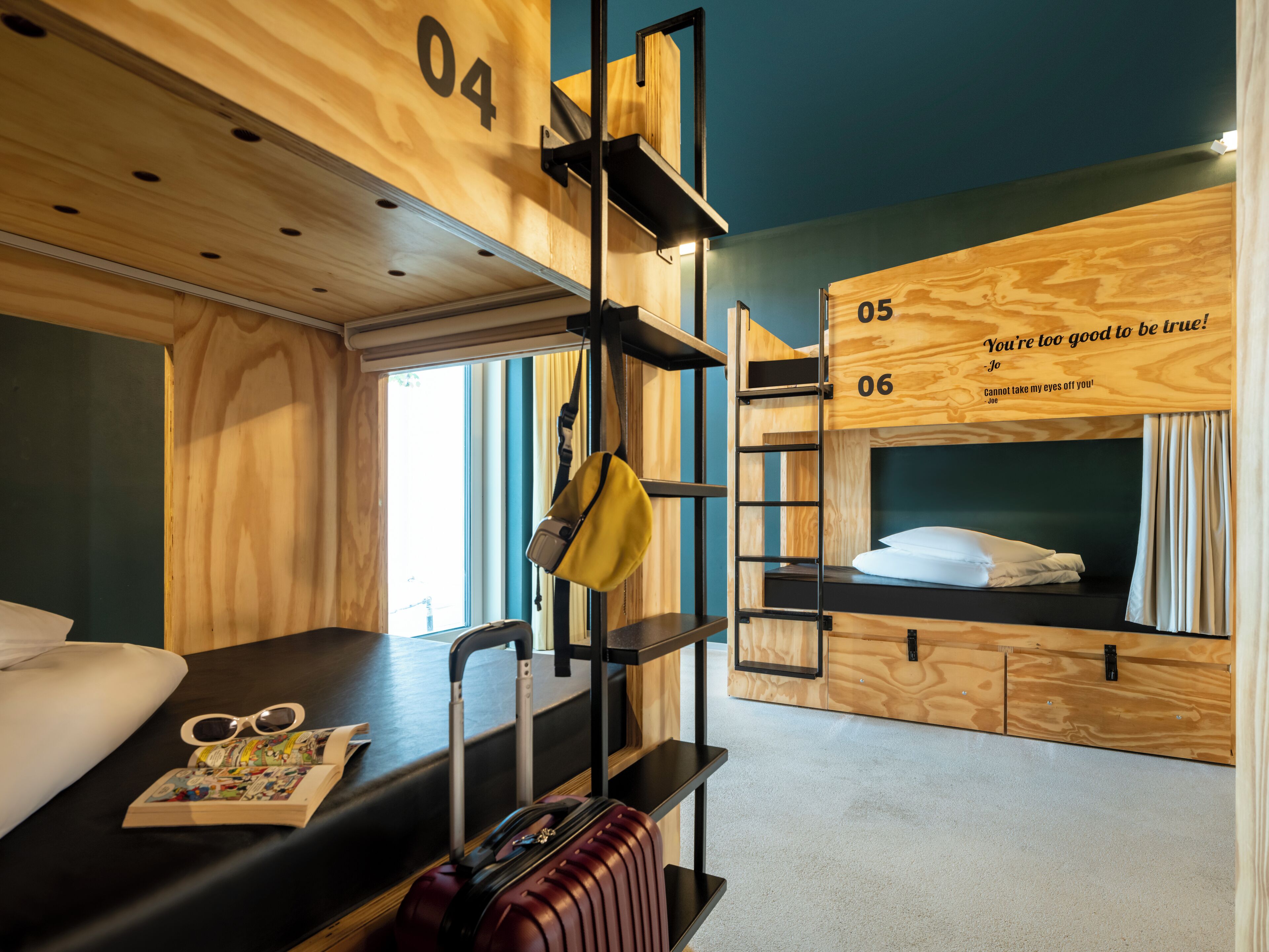 A bunk bed room with a suitcase, a pair of sunglasses, and a book on the bed.