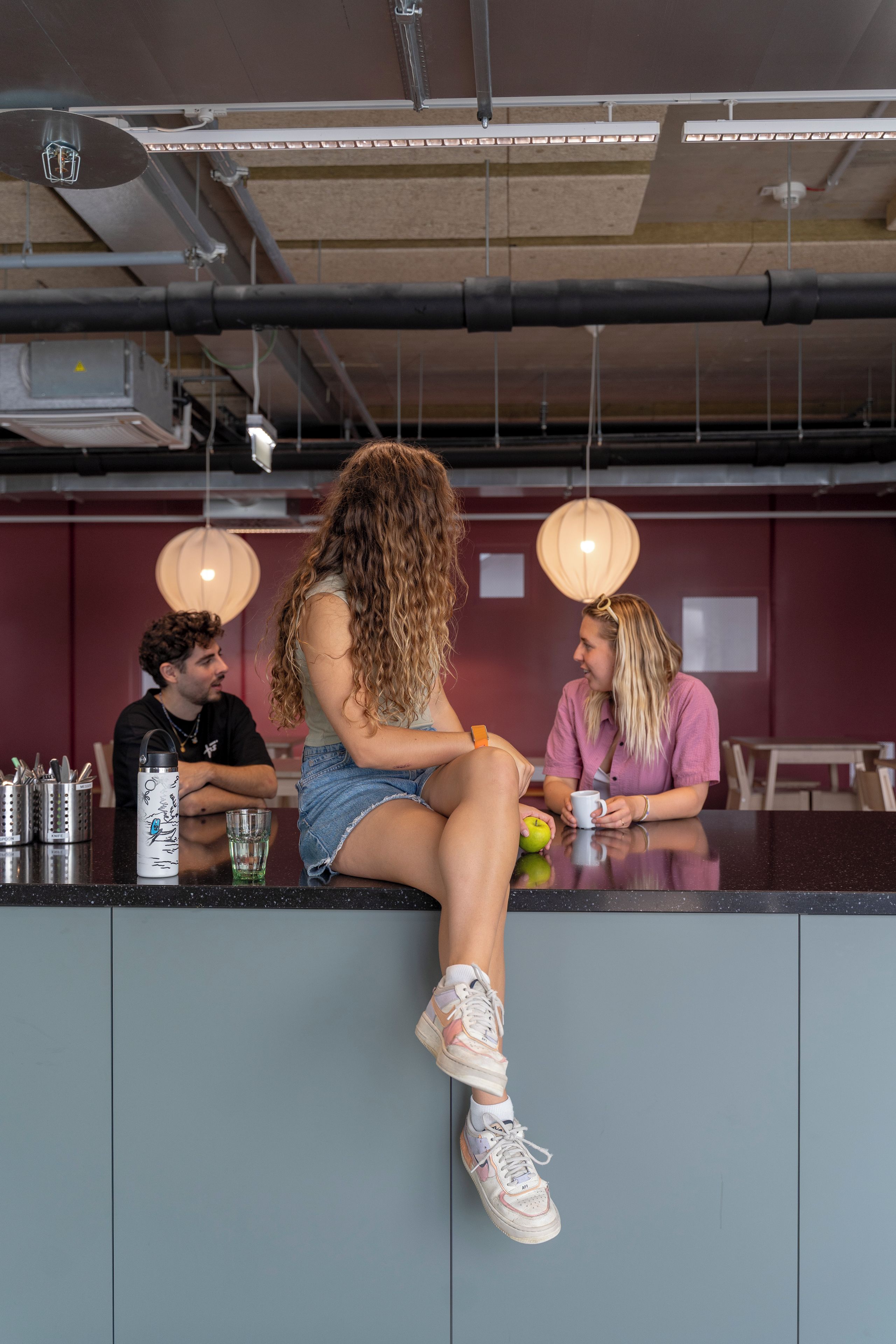 A bar area with a counter, seating, and hanging lights.