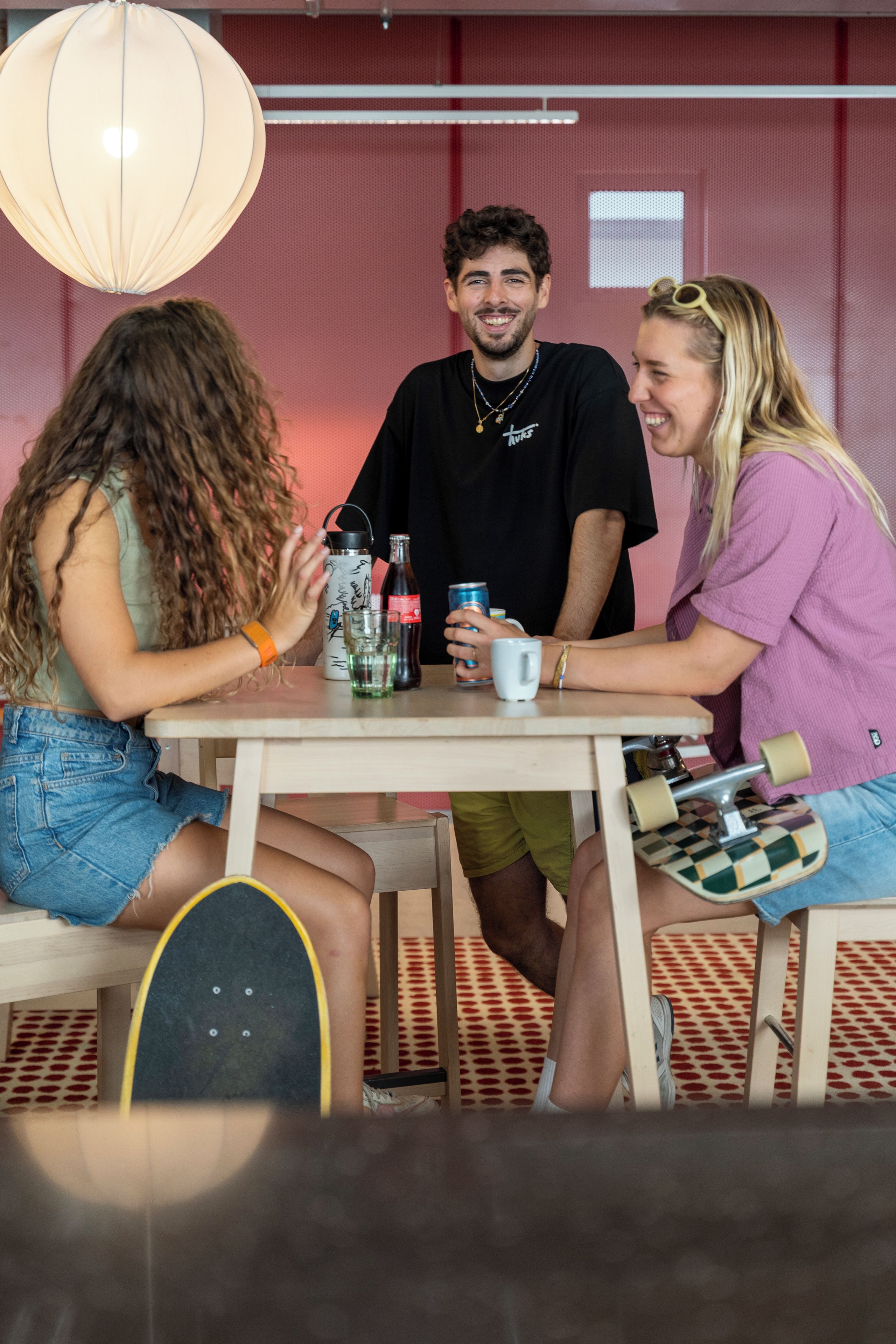 A group of people sitting at a table with drinks and a skateboard.