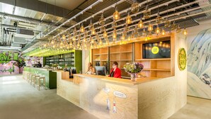 A reception area with a wooden counter, bar stools, and a mural on the wall. - JO&JOE Vienna - Hostel (Vienna)