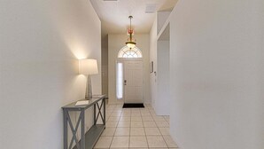 A hallway with a door, a light fixture, and a console table.