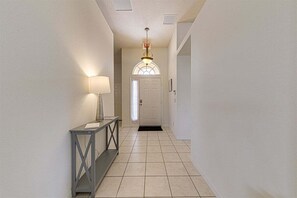 A hallway with a door, a light fixture, and a console table.