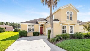 A single-story house with a red door, a covered front porch, and a well-maintained lawn.