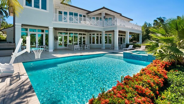 A two-story house with a swimming pool, outdoor seating, and a covered patio area.