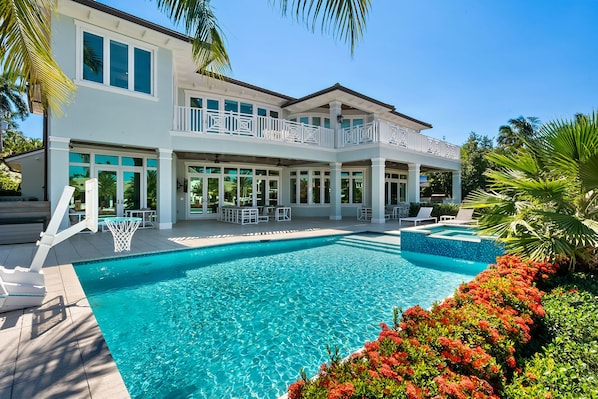 A two-story house with a swimming pool, outdoor seating, and a covered patio area.