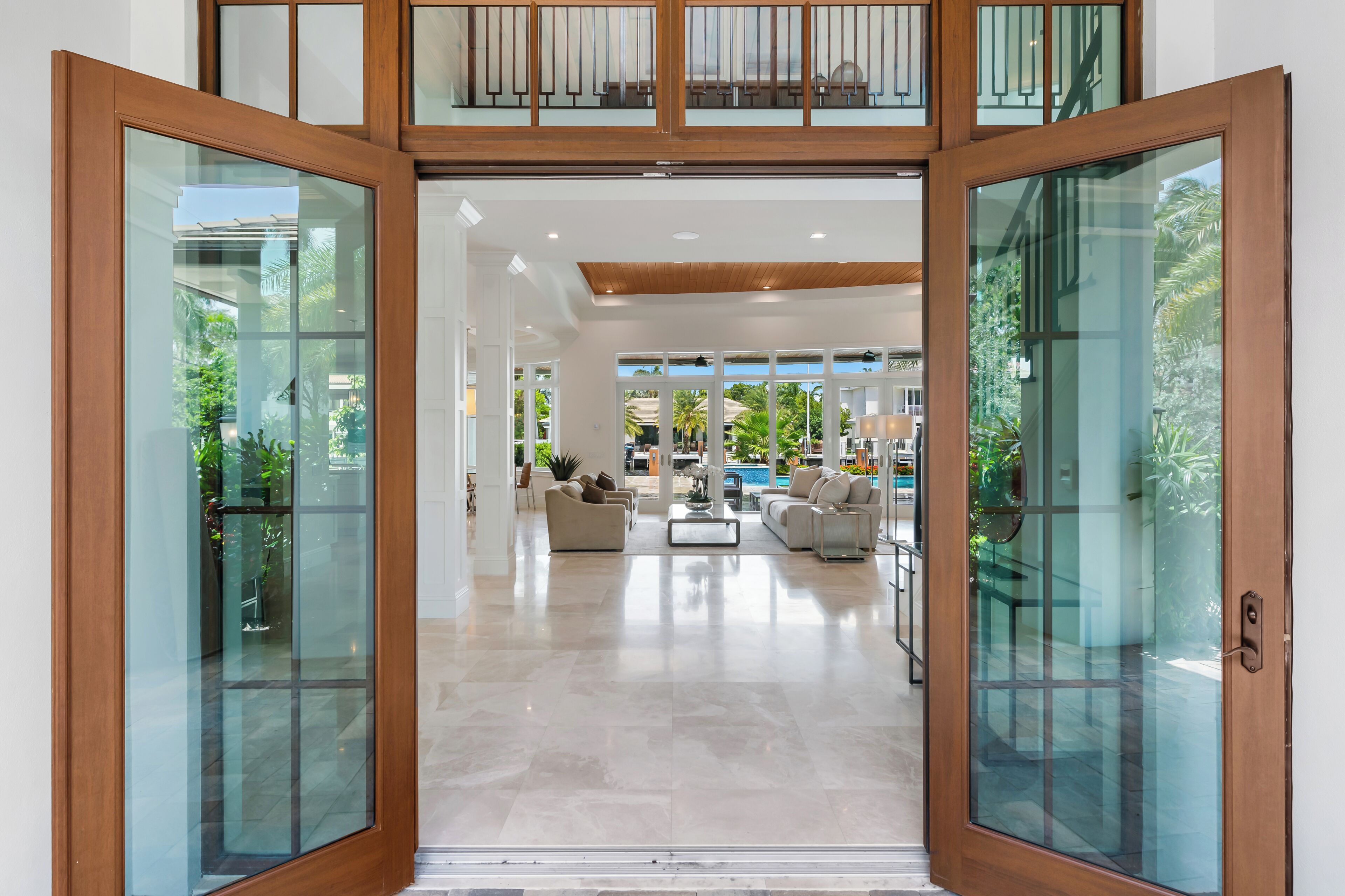 A spacious living area with a high ceiling, a pool, and a view of the outdoors.