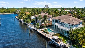 A waterfront property with a large house, a swimming pool, and a dock with boats.