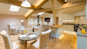 A spacious kitchen with wooden beams, a dining area with a round table, and a bar area.