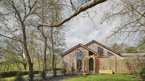 A rustic wooden cabin with a large window and a wooden deck. - Honister Cottage - Luxury Cottages (Kendal)