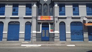 A hotel with a central entrance, blue doors, and a signboard advertising a restaurant. - Hotel Michel (São Paulo)