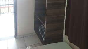 A bedroom with a wardrobe, a bed, a television mounted on the wall, and a view of the outside balcony. - Hotel Michel (São Paulo)