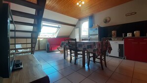 Una cocina con una mesa de comedor, sillas, un sofá rojo y un ventanal.