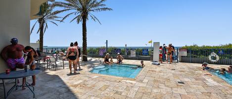 A pool area with multiple pools, palm trees, and a clear sky.