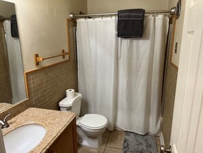 Een badkamer met een witte wastafel, toilet en douchegordijn.