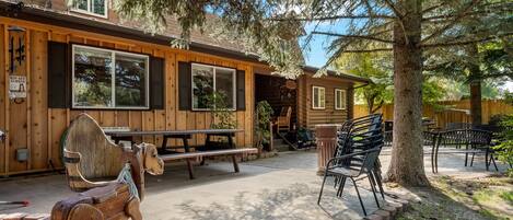 A log cabin with a wooden exterior, a picnic table, outdoor seating, and a rocking horse.