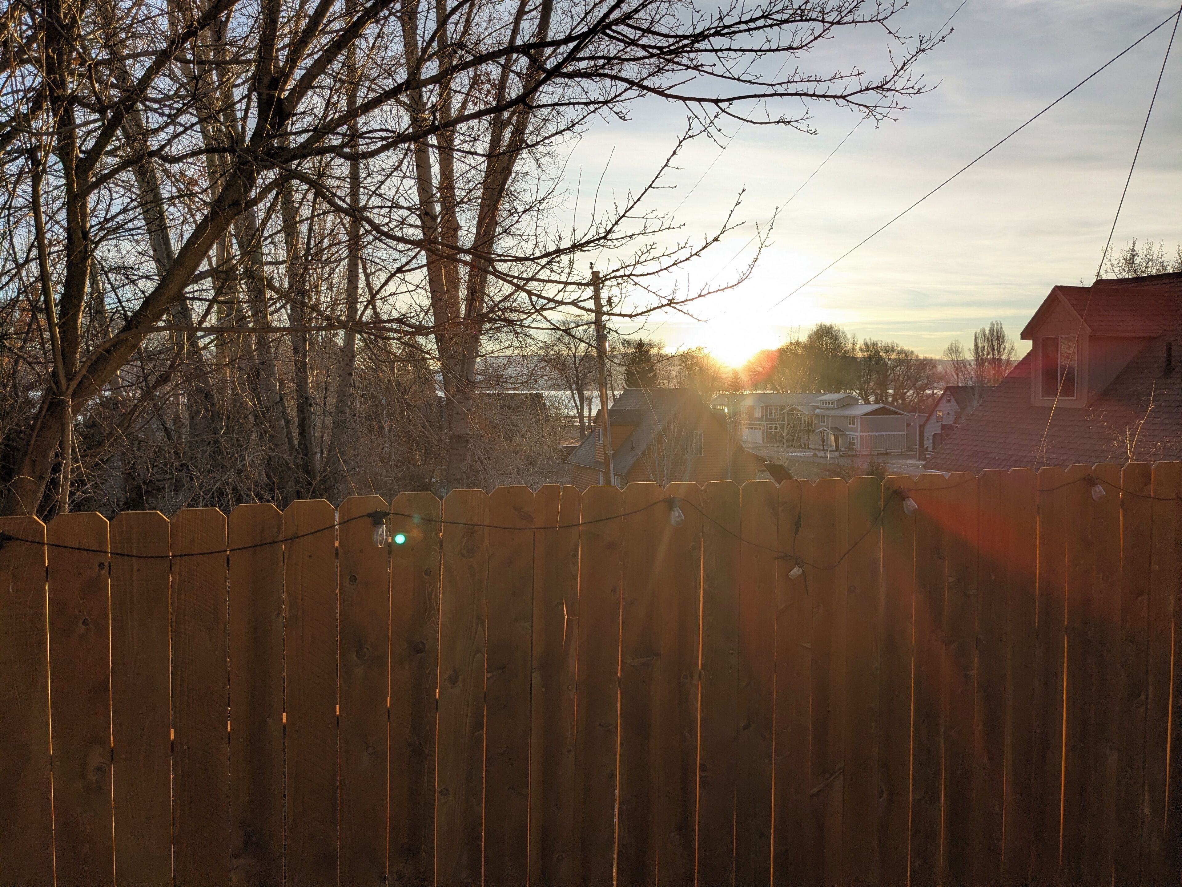 A wooden fence with a view of houses and trees in the background.