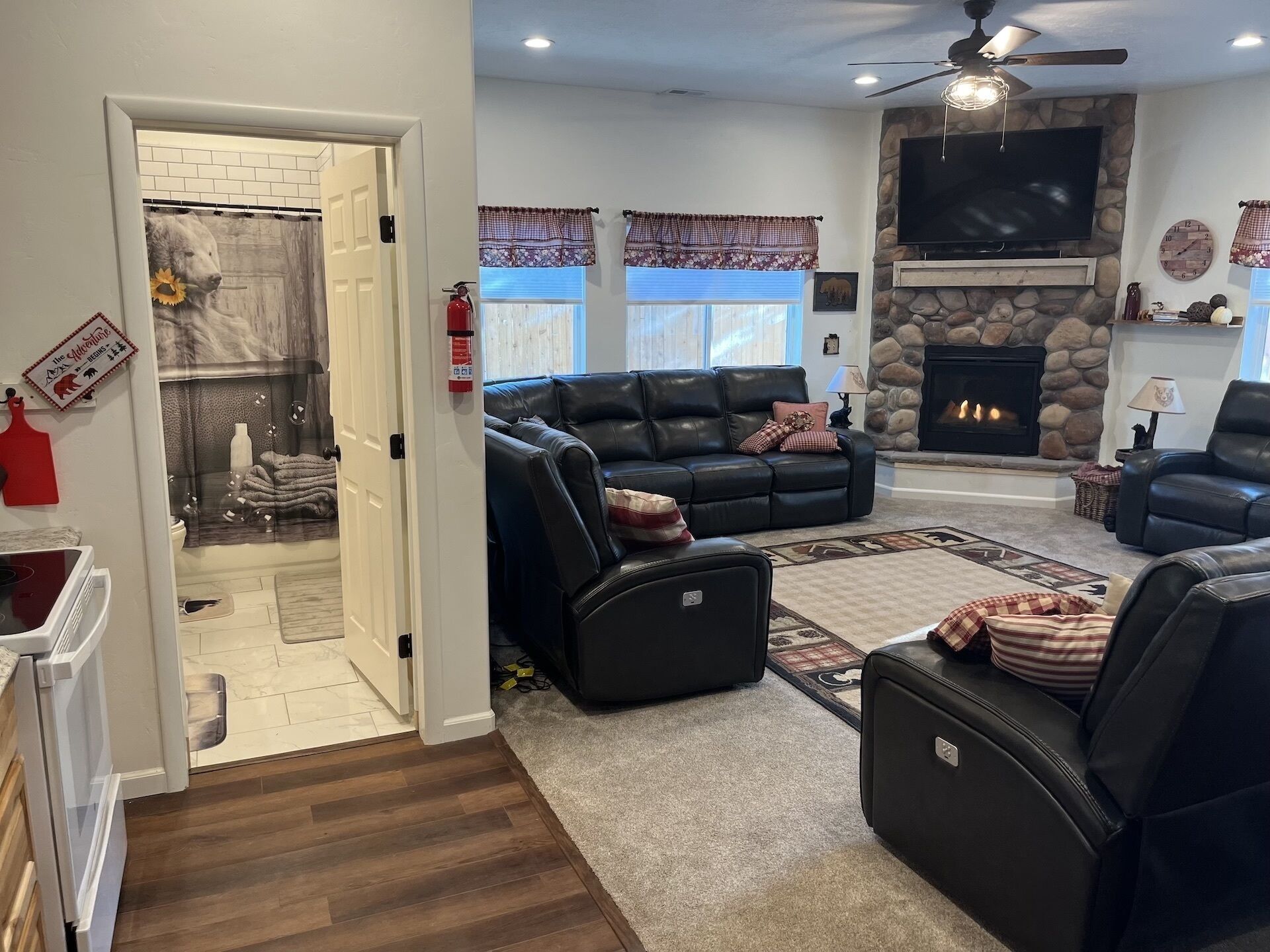 A living room with a fireplace, leather sofas, and a stone wall.
