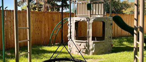 A playground with a swing set, a slide, and a climbing structure.