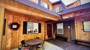 A wooden cabin with a patio area featuring a round table and chairs, a door, and a window. - MAMA BEAR CABIN -RUSTIC LOG  Cabin Retreat -  Boat Parking - All Size Groups (Garden City)