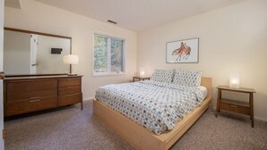 A bedroom with a bed, a dresser, a mirror, a window, and a wall-mounted artwork. - JHRL - Slope-side Whiteridge B1 Condo - Walk to Tram (Teton Village)