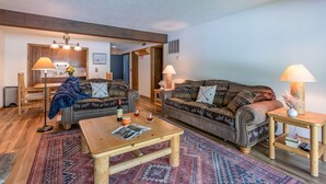 A cozy living room with two patterned sofas, a wooden coffee table, and a rug.