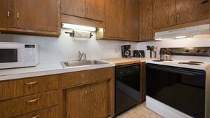 A kitchen with wooden cabinets, a microwave, a sink, a dishwasher, a stove, and a coffee maker.
