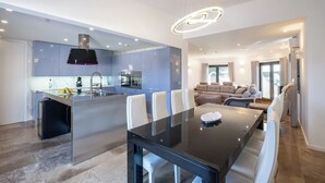 A modern kitchen with a central island, a dining area with a glass table, and a living space with a sofa and a fireplace. - BELO HORIZONTE  by Dreamplaces (Lagoa)