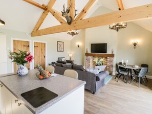 A modern kitchen with a granite countertop, a built-in oven, and a dining area with a brick fireplace. - Stag Cottage at Broadings Farm (Whitby)