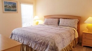 Une chambre à coucher avec un grand lit, deux lampes de chevet, une table de chevet et un tableau encadré au mur.
