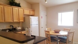 Une cuisine avec des meubles de rangement en bois, un réfrigérateur, un évier, une cuisinière et une table à manger avec des chaises.