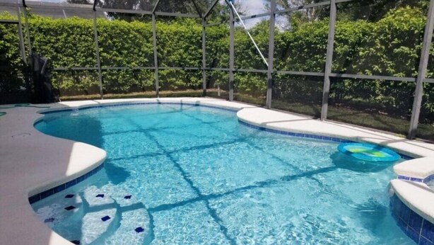 Une piscine avec un bord carrelé et une clôture périphérique.