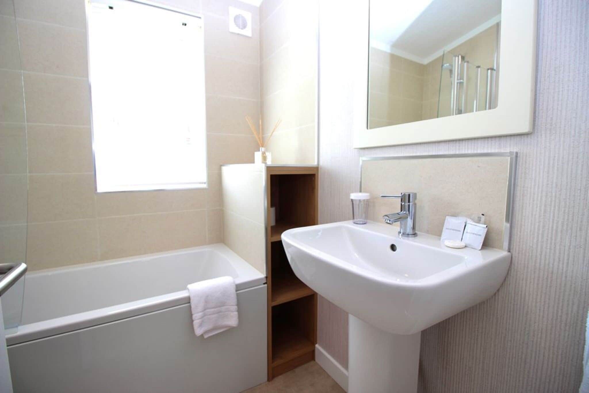 A bathroom with a bathtub, a sink, and a mirror.