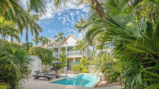 A pool area with lounge chairs and a building with a balcony. - ~Reel Paradise~Beautiful private townhouse in a small gated community. (Key West)