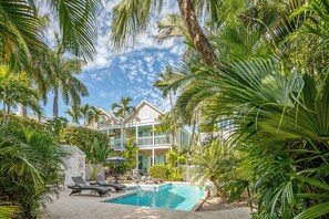 A pool area with lounge chairs and a building with a balcony. - ~Reel Paradise~Beautiful private townhouse in a small gated community. (Key West)