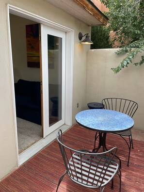 A patio with a round table and two chairs, a sliding glass door, and a wall-mounted light fixture. - Location, Location, Location! Downtown Santa Fe (Santa Fe)
