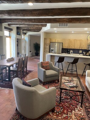 A spacious living area with a dining table, comfortable seating, a kitchen with wooden cabinets, and a large window. - Location, Location, Location! Downtown Santa Fe (Santa Fe)