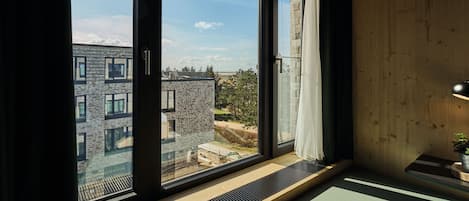 A modern room with large windows, a wooden ceiling, and a view of buildings outside.