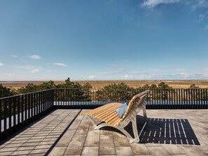 Un banco de madera con cojín en un patio con baldosas, con vistas a un paisaje extenso.